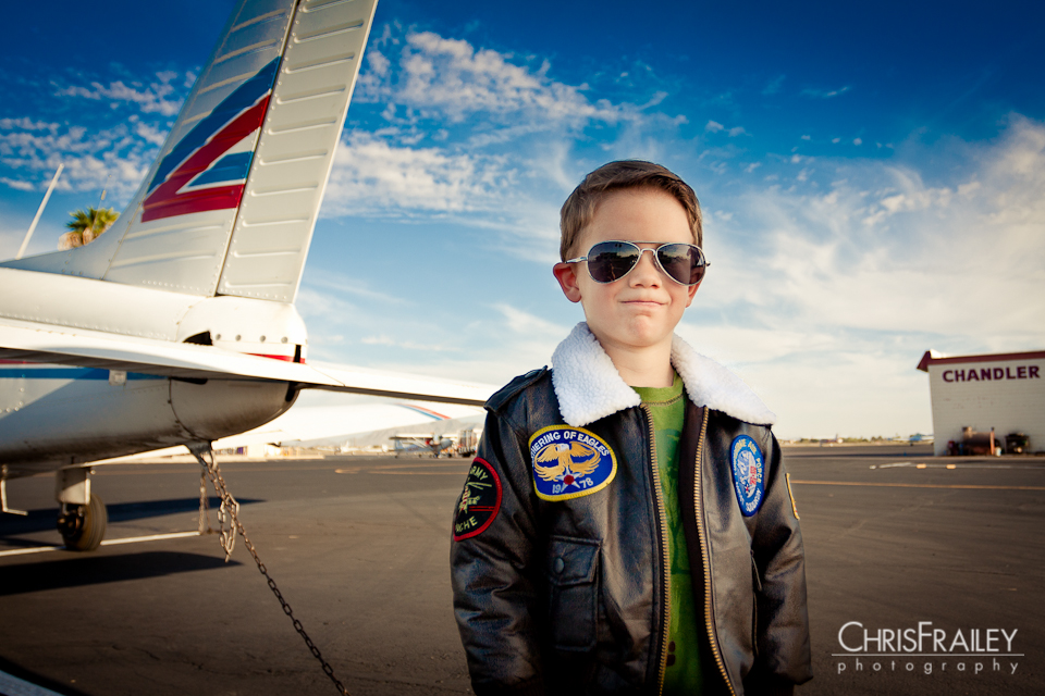 A young boy wearing a WW 2 bomber jacket at an airport.