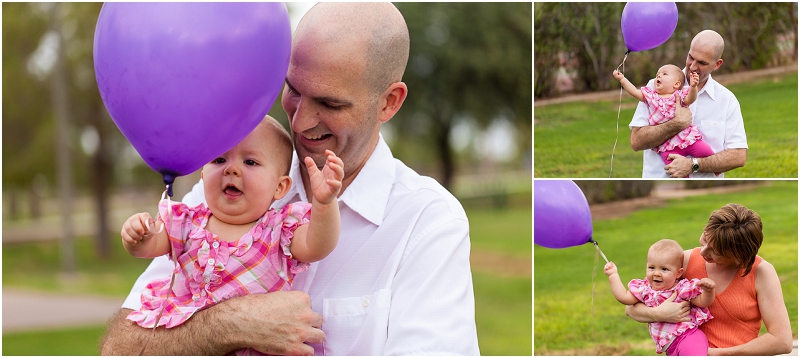 A father holding his daughter who is playing with a purple balloon. 