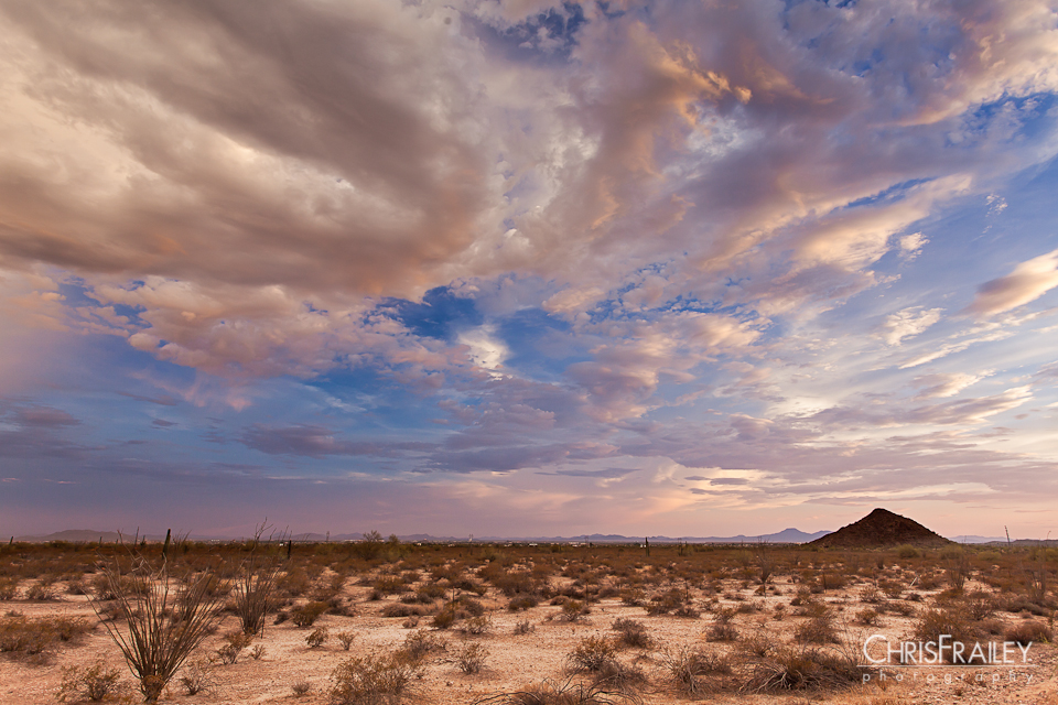 Scattered clouds highlight the setting sun on the Arizona desert.