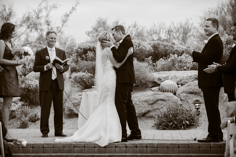 A bride and groom kissing during their ceremony.
