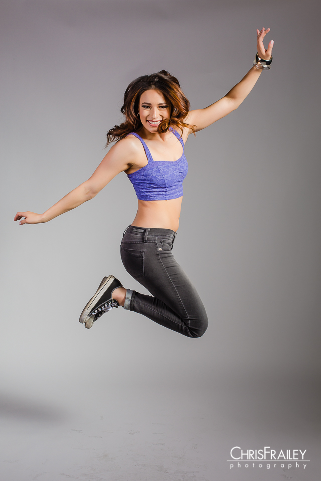 Fashion model jumping in the air during a studio shoot wearing Converse shoes. 