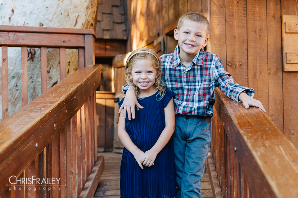 A brother and sister standing on a wooden walkway family pictures at the Phoenix Zoo.