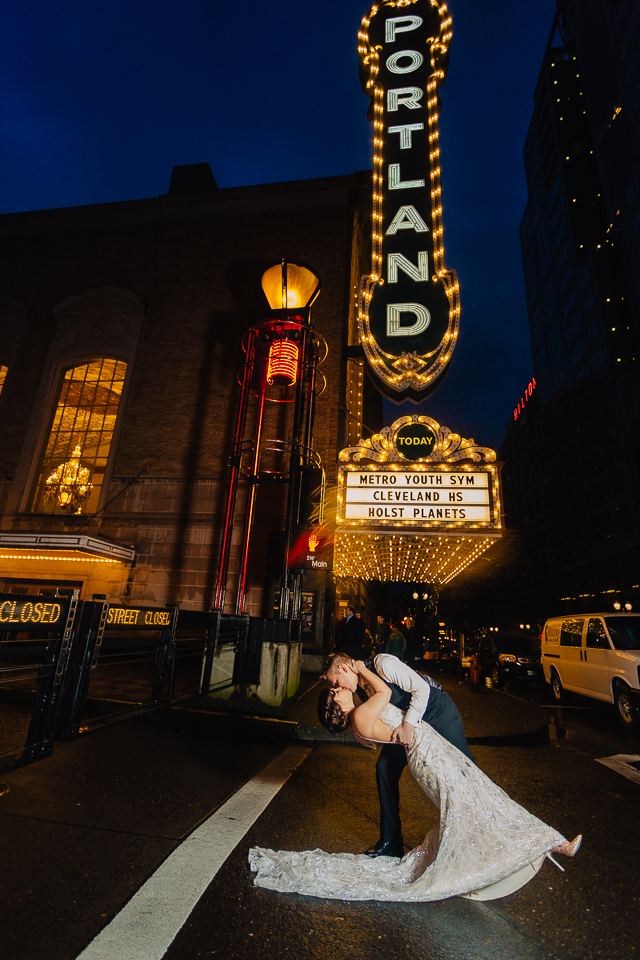 Bride and groom dipping in front of Portland Theater sign.