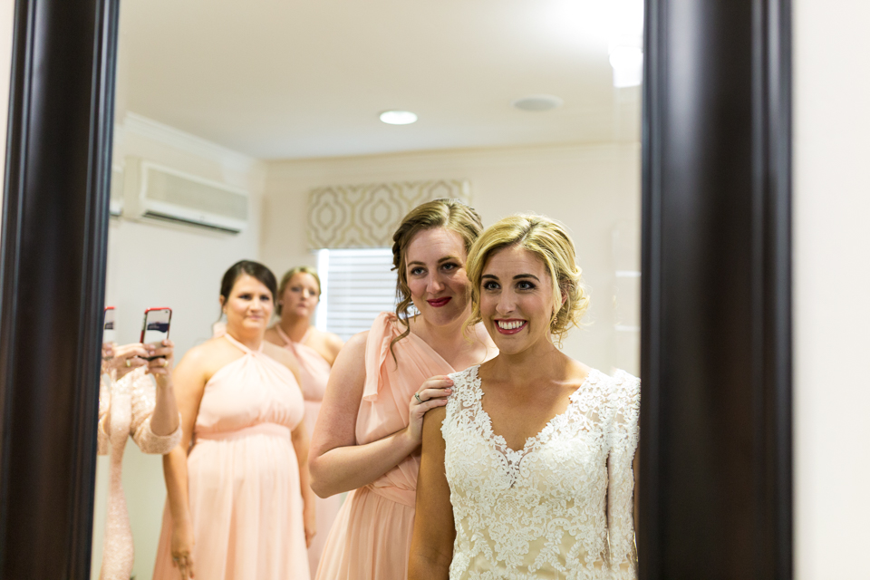 Bridesmaids looking into mirror with bride.