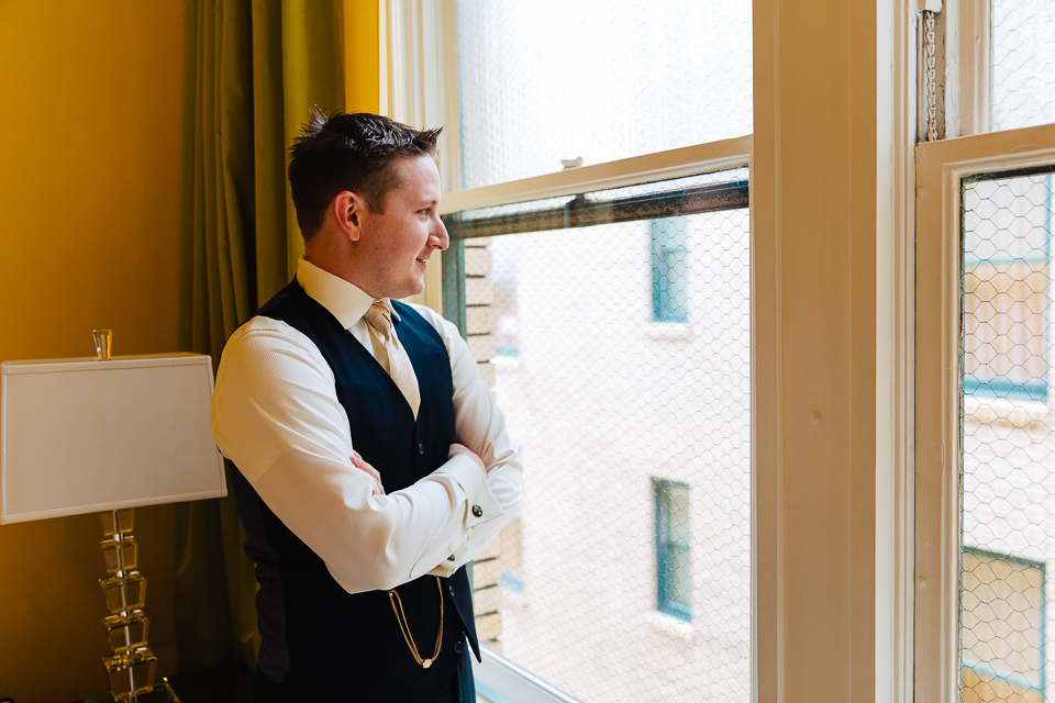 Groom staring out hotel window.