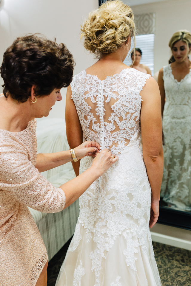 Mother of bride buttoning up bride's dress.