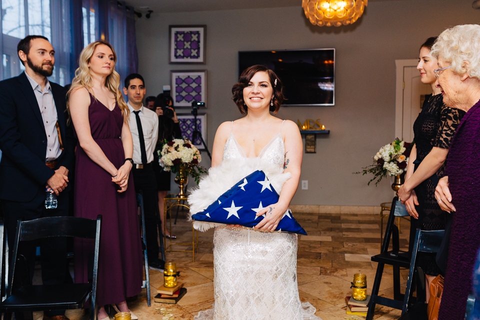 Bride walking down aisle carrying American flag.
