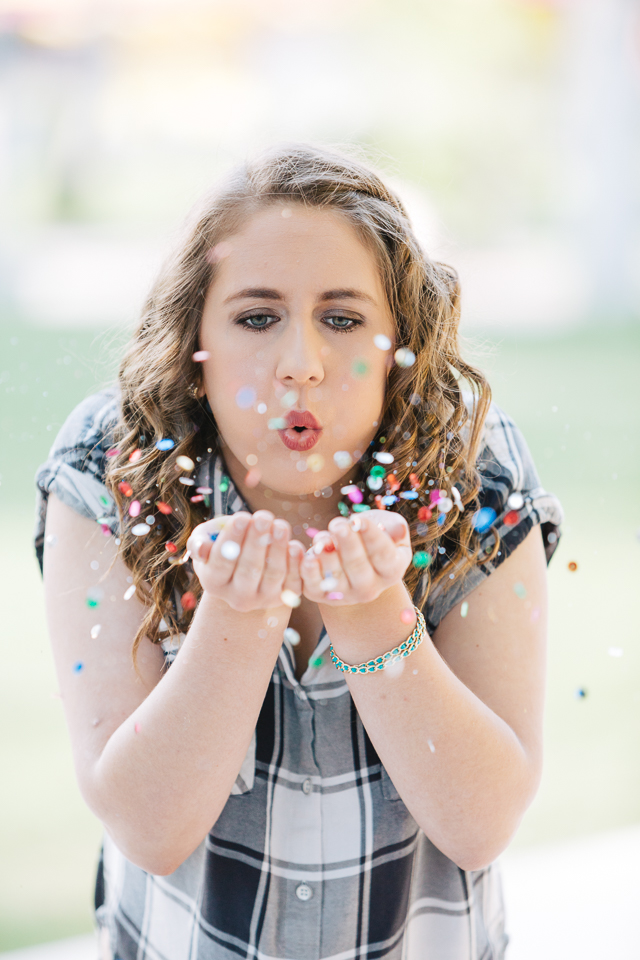 High school senior girl blowing glitter. 