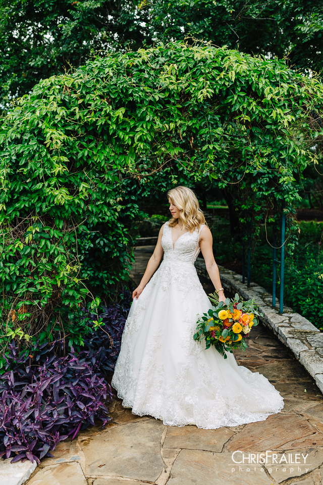 Bride standing under a floral arch at the Fort Worth Botanic Garden in Fort Worth Texas.