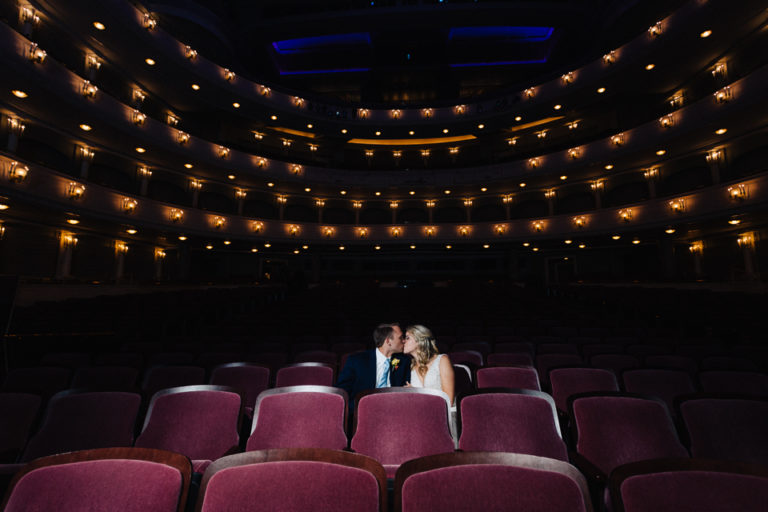 Bride and groom kissing in theater seats of Bass Hall.