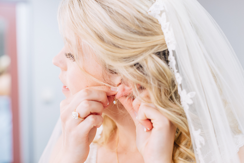 Bride putting on her earrings. 