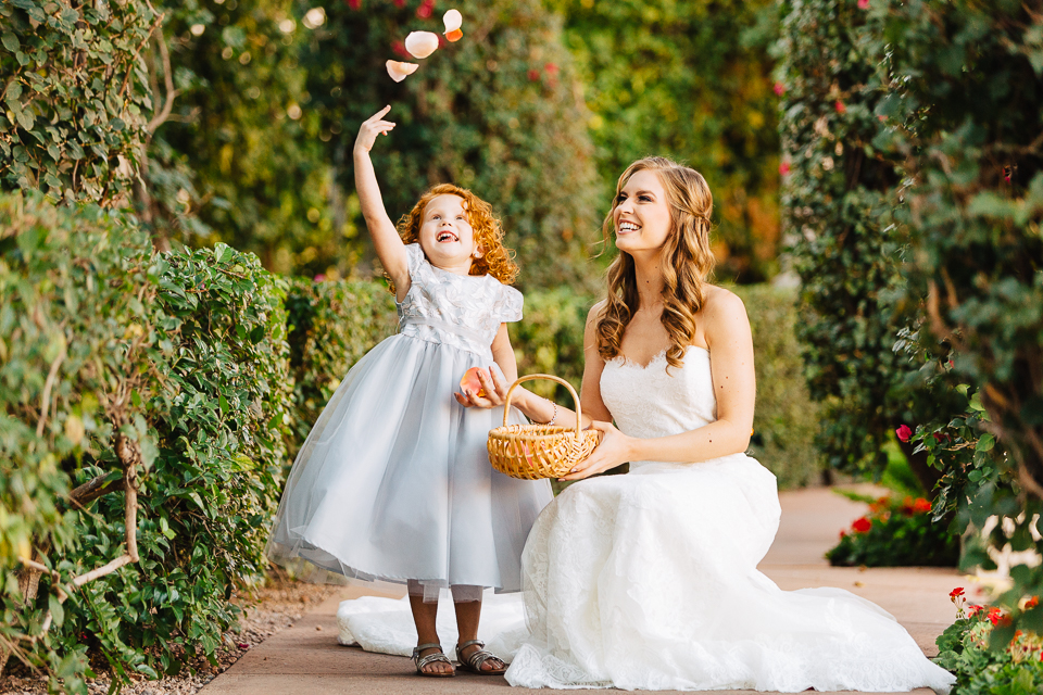 Flower girl throwing rose petals into the air.