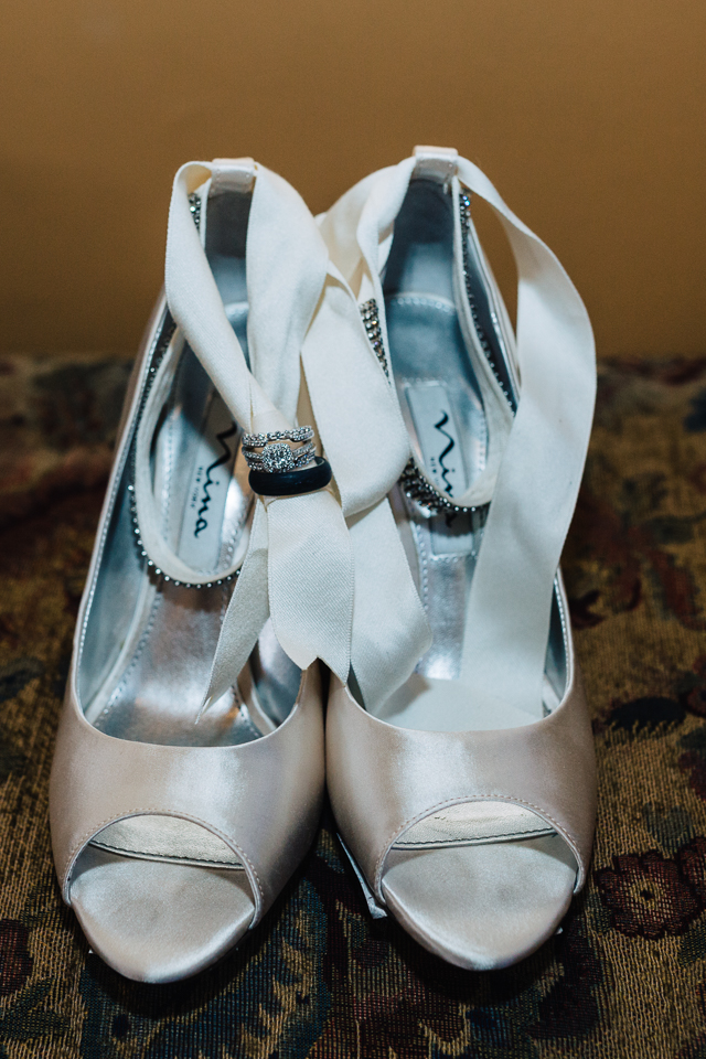 Bride's wedding shoes with wedding rings tied onto shoes.