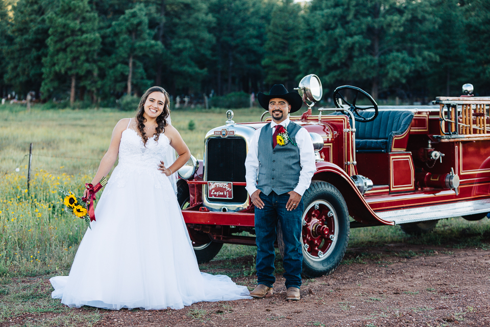 Bride and groom posing in a meadow with an America LaFrance firetruck.