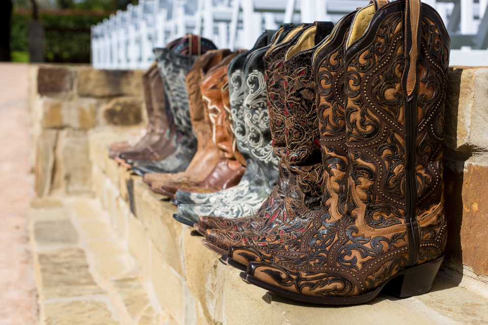 Bride and bridesmaid's cowboy boots lined up on a bench at The Springs Event Venue's Westwood Hall.