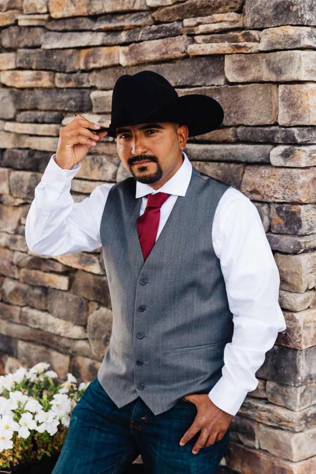 Groom posing in black cowboy hat. 