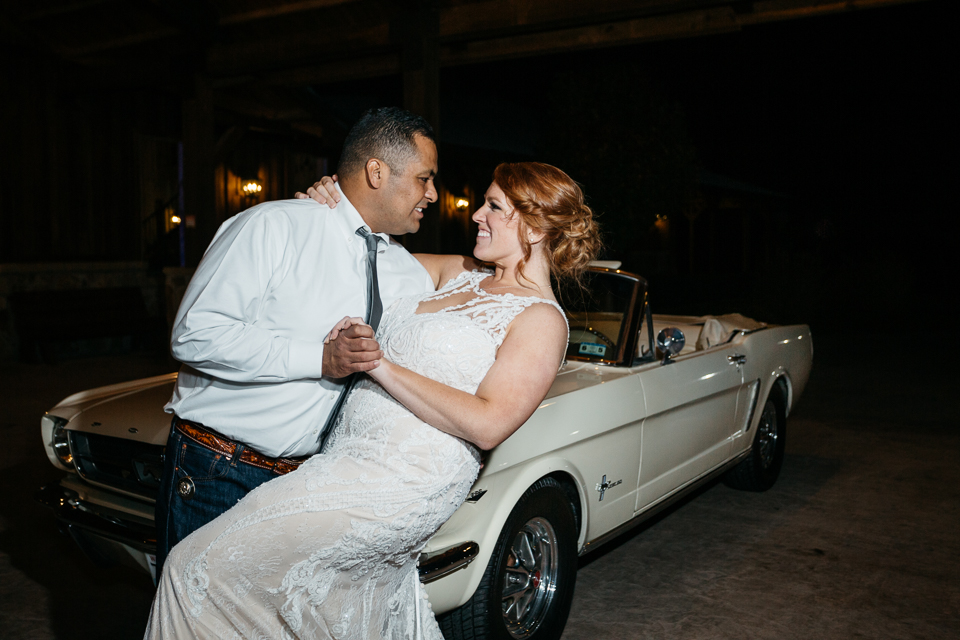 Groom dipping bride in front of 65 Ford Mustang.