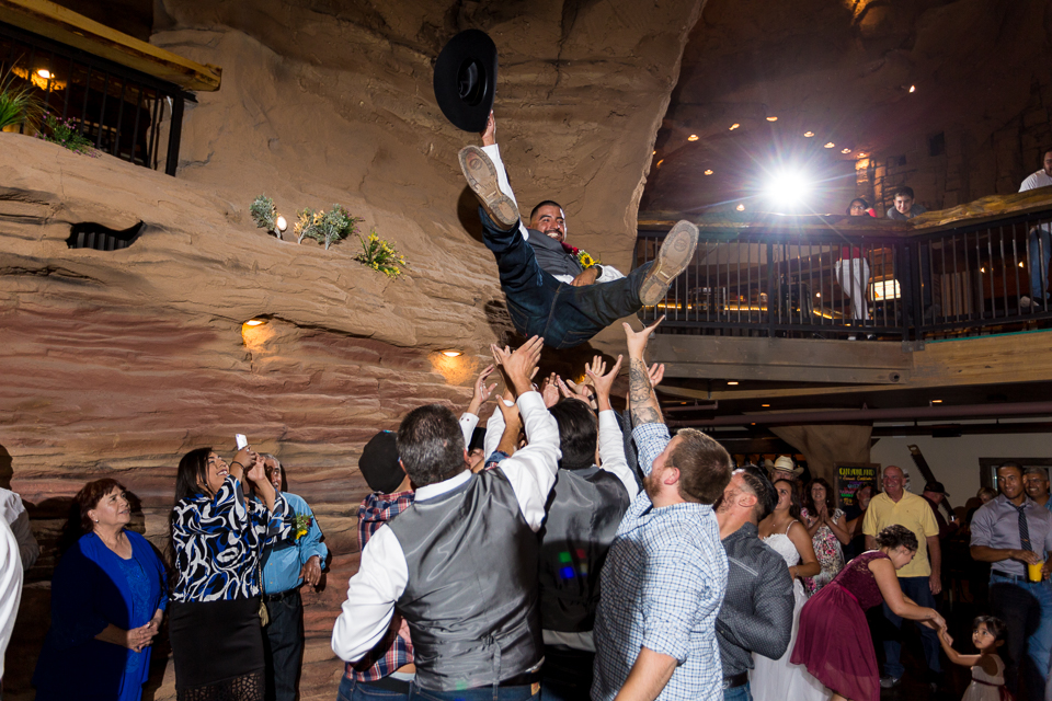 Groomsmen tossing groom into air during wedding reception. 