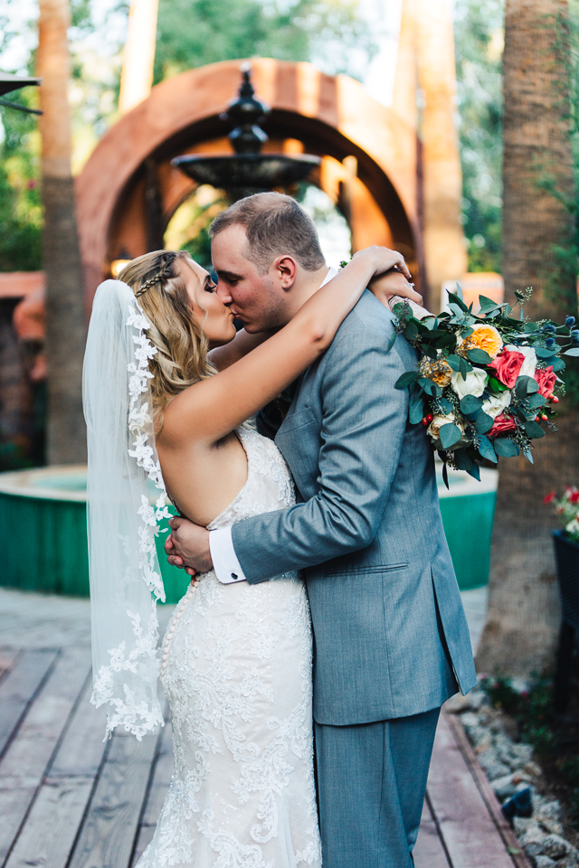 Bride and groom kissing in front of a fountain.