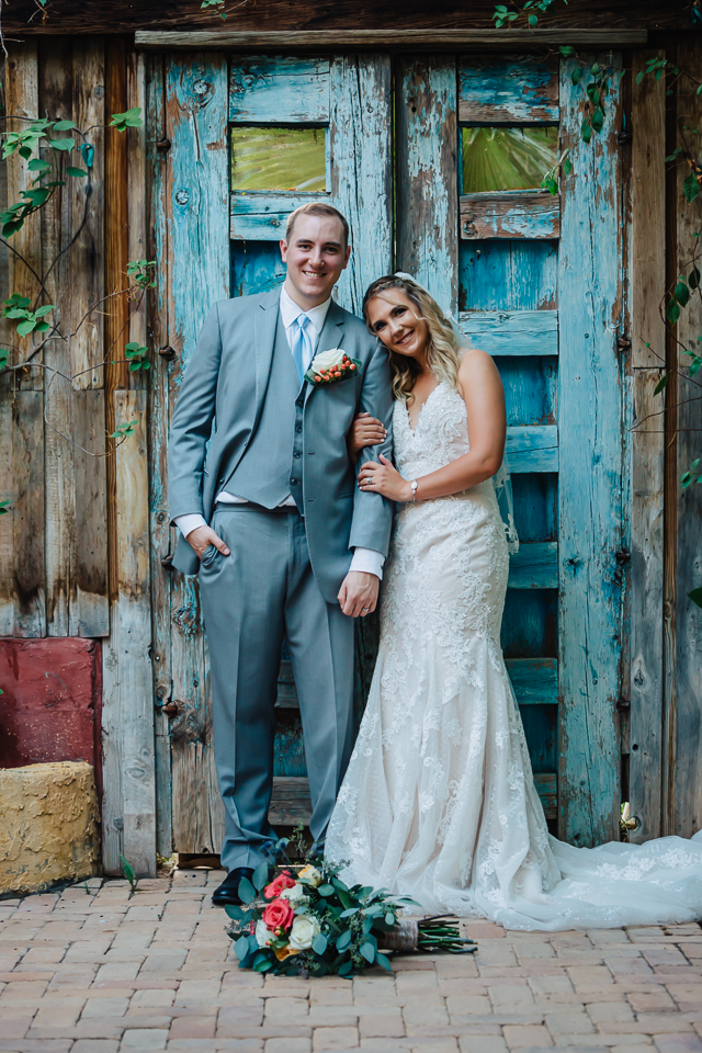 Bride and groom posing in front of blue door at Boojum Tree wedding. 