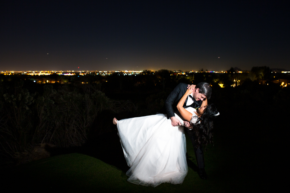 Groom dipping his bride for a kiss with the Phoenix city lights off in the background.