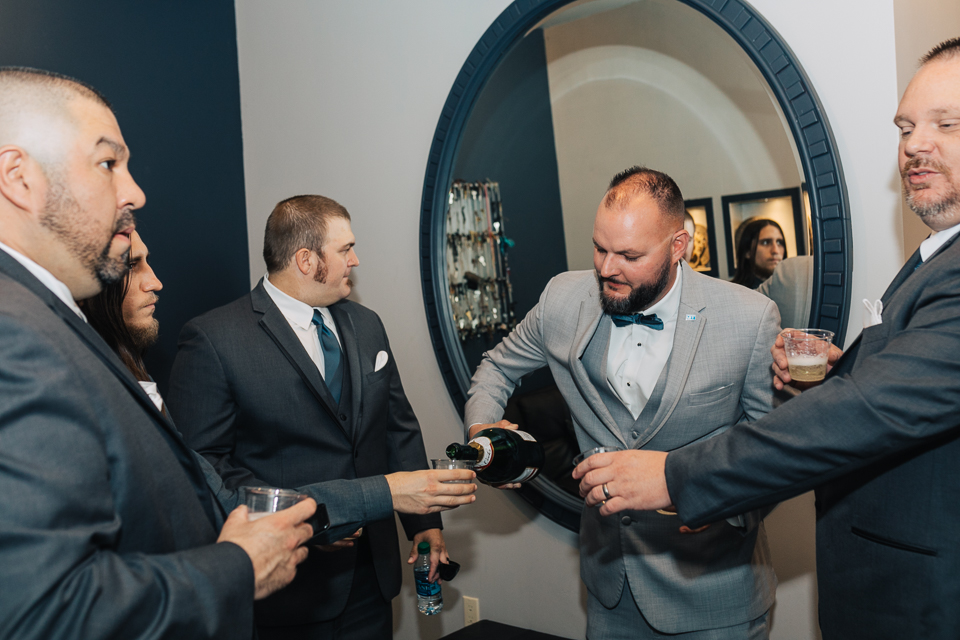 Groom and groomsmen celebrating with a drink.