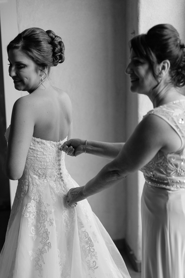 Bride's mother helping her with her wedding dress. 