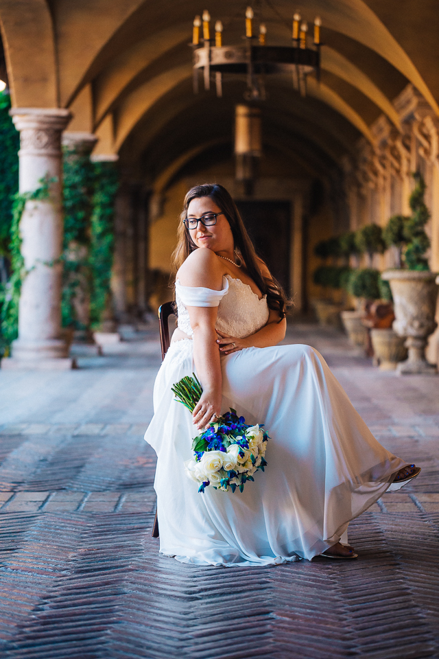 Bride posing in a chair while holding bouquet in the courtyard area of Villa Siena. 