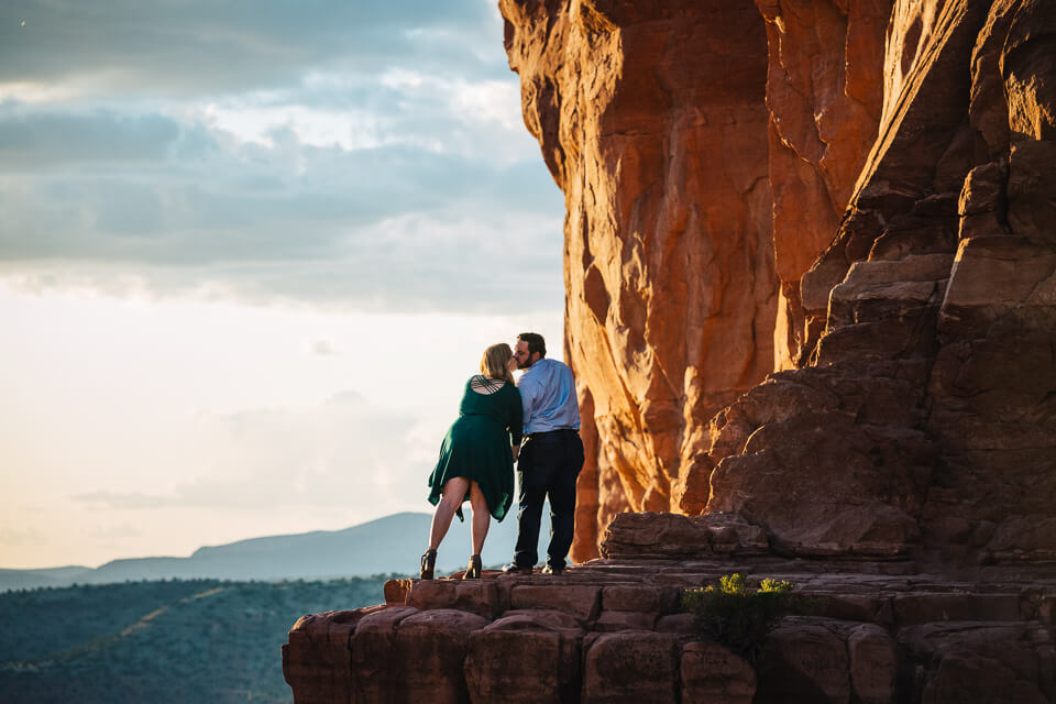 Engaged couple staring into the sunset on top of the Cathedral Rock Trail. 