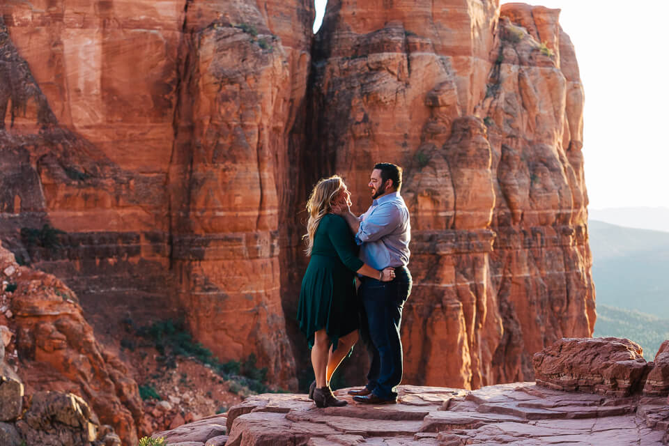 Engaged couple embracing on outcropping of rock at Cathedral Rock.