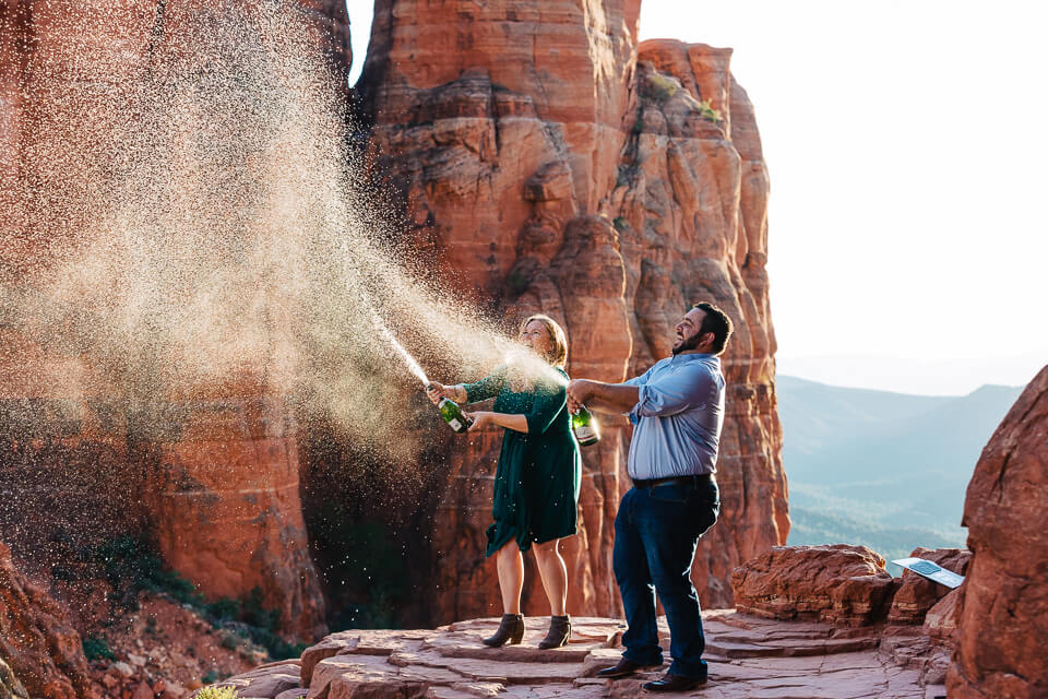 Engaged couple spraying champagne bottles for their engagement photos. 