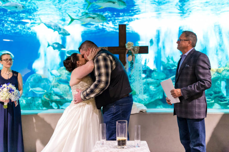 Bride and groom kissing during their wedding ceremony at the OdySea Aquarium.