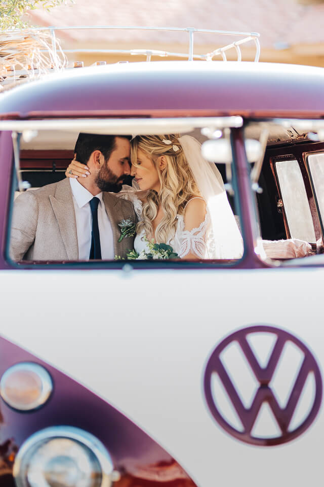 Bride and groom staring at each other while sitting in a VW bus.