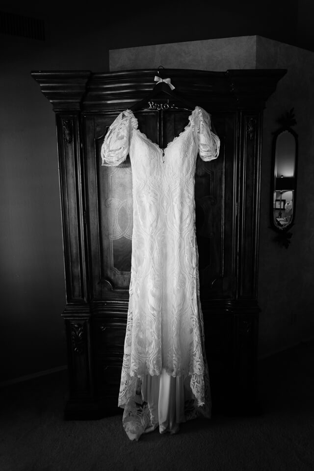 Black and white photo of the bride's wedding dress hanging.