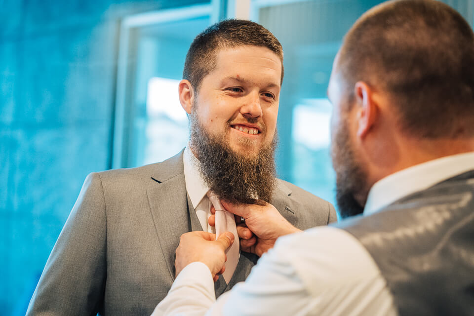 Bestman helping groom with his tie. 