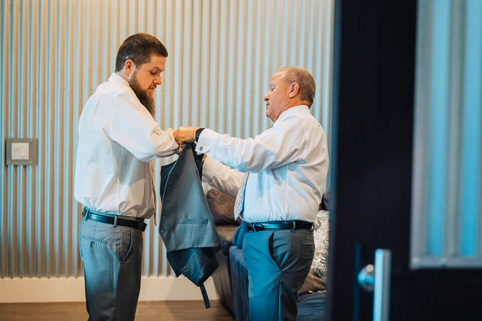 Groom's father helping him with his jacket.