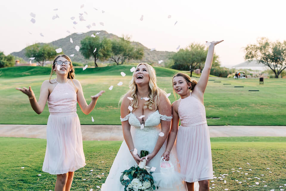 Bride throwing rose petals in the air with the flower girls. 