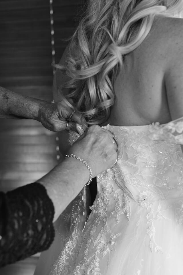 Bride's mother buttoning up her wedding dress. 