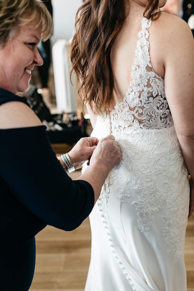 Mother of bride zipping up bride's dress.