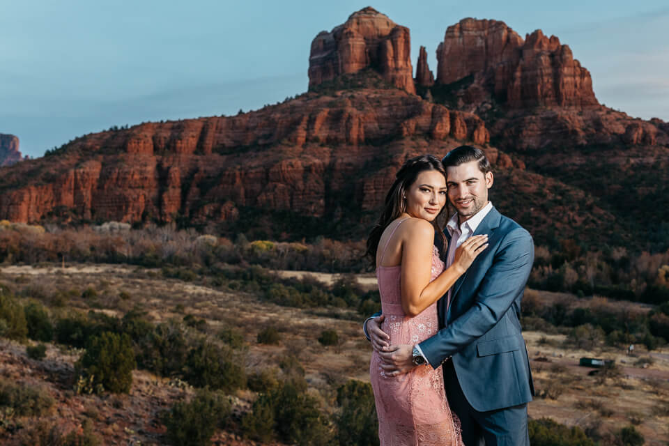 Couple embracing in front of Cathedral Rock during sunset in Sedona. 