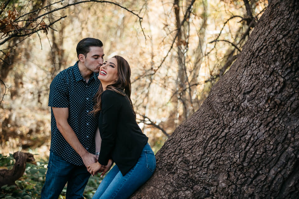 Guy kissing his fiancé on the cheek at Oak Creek Sedona Arizona. 