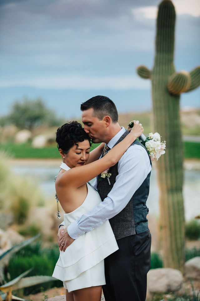 Couple kissing in front of a saguaro cactus.