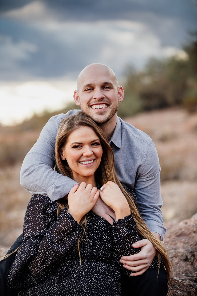 Couple sitting on a rock holding each other at Papago Park.