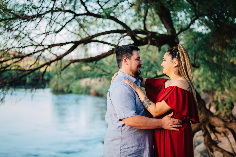 Couple holding each other while standing near the Salt River.
