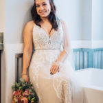 Bride posing by a bathtub holding her bouquet.