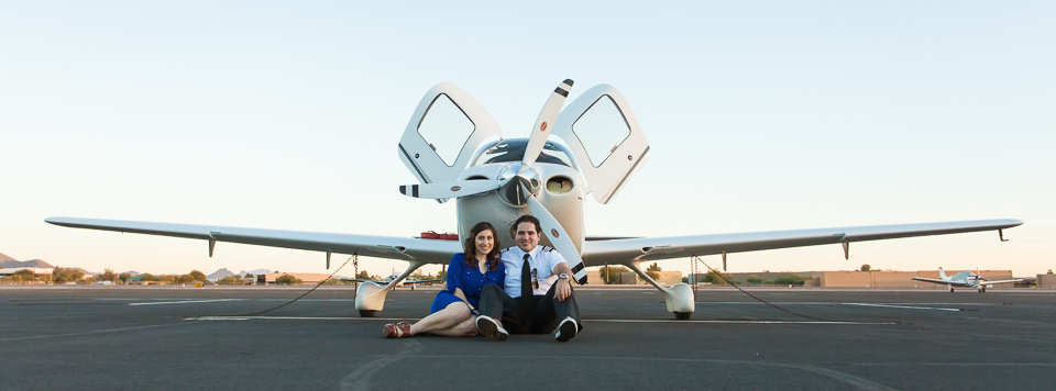Couple sitting in front of a small airplane.