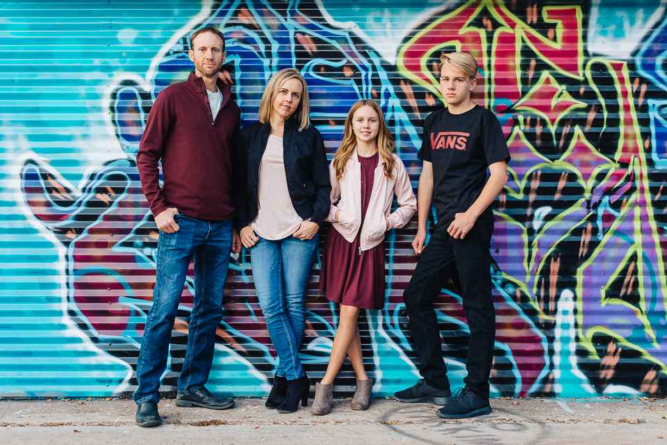 Family of four posing against a graffiti wall.