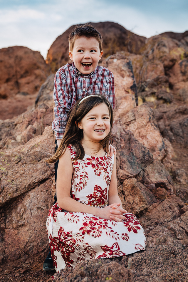 Brother and sister posing on rocks.