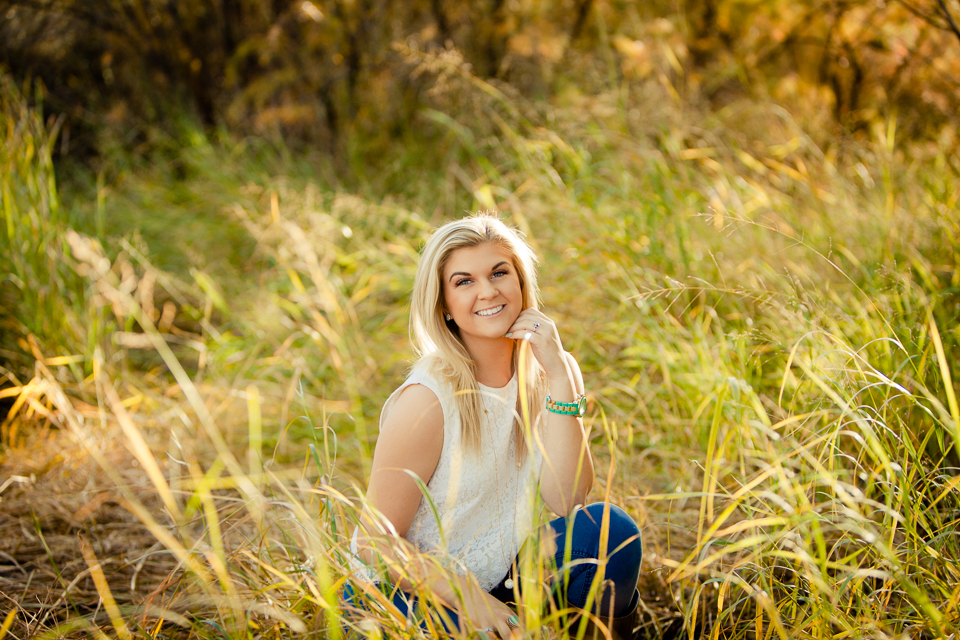 Senior girl posing in grassy field.