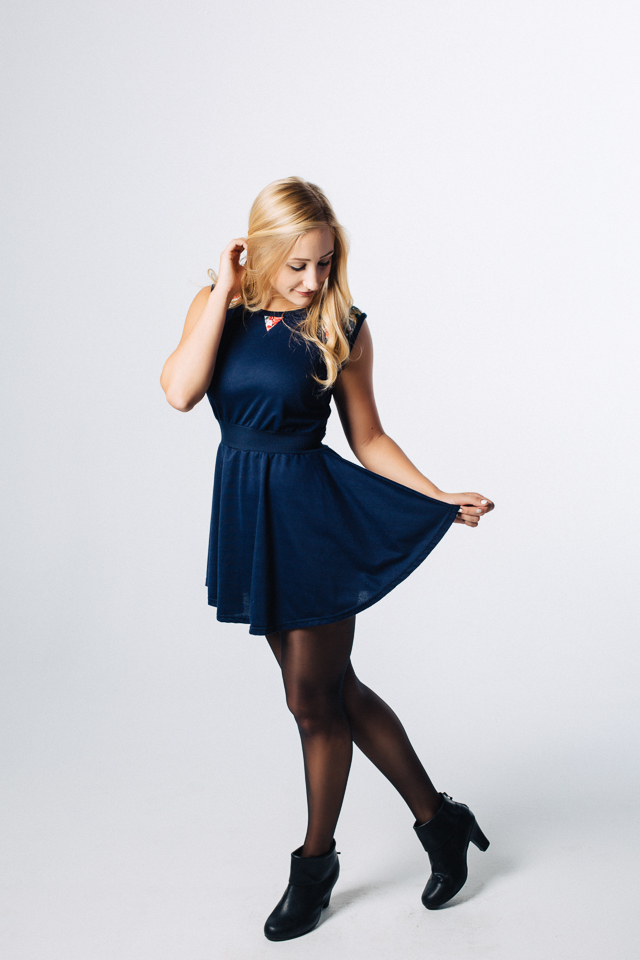 Model wearing a dark blue dress looking down.